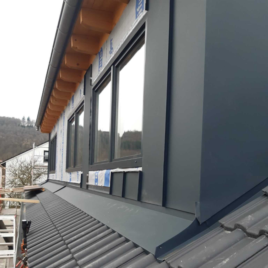 Dachgaube mit anthrazitfarbener Metallverkleidung und großen Fenstern auf einem modernen Steildach. Hochwertige Dachgauben-Verkleidung für optimalen Witterungsschutz und ansprechendes Design.