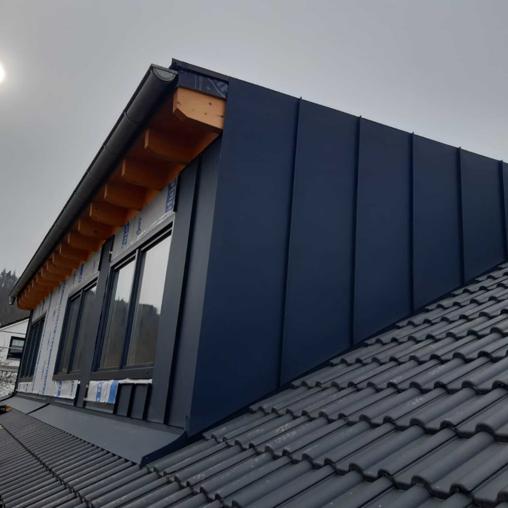 Dachgaube mit anthrazitfarbener Metallverkleidung und großen Fenstern auf einem modernen Steildach. Hochwertige Gaubenverkleidung für optimalen Witterungsschutz und ansprechendes Design.
