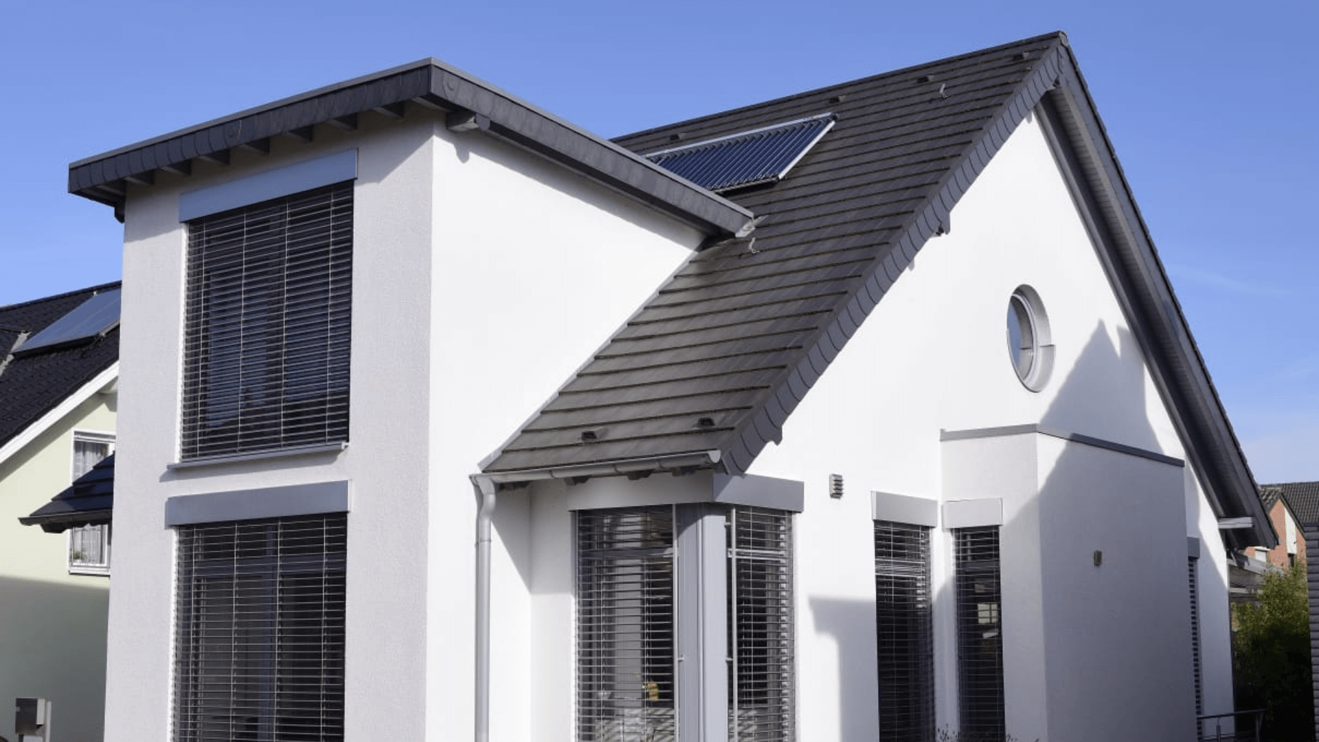 Modernes Einfamilienhaus mit dunkelgrauer Dacheindeckung, integrierter Solaranlage und eleganter Fassadengestaltung. Effiziente Dachlösungen für nachhaltiges Wohnen.